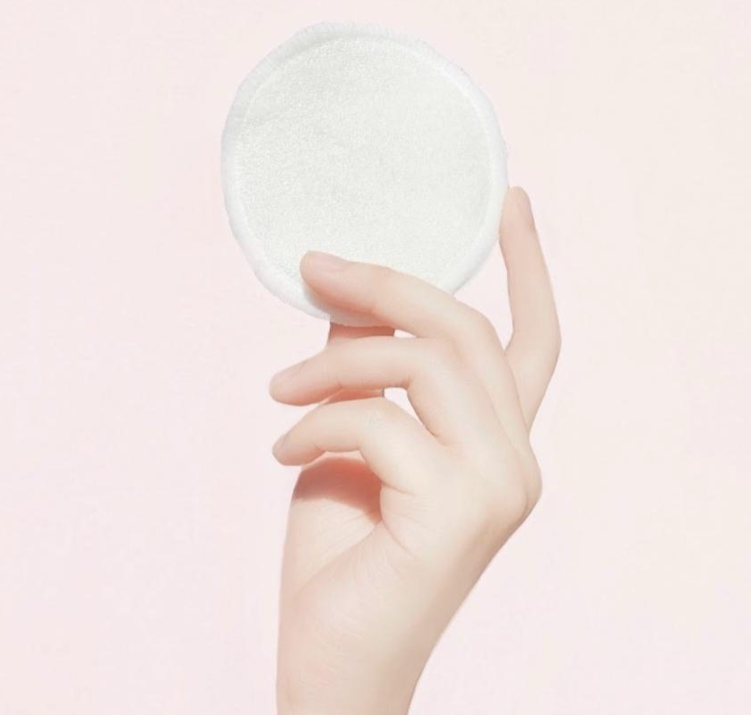 ID: a hand holding up a round Meiyu makeup wipe